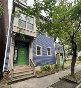 Exterior of the NATURE Lab building is blue with a green door.